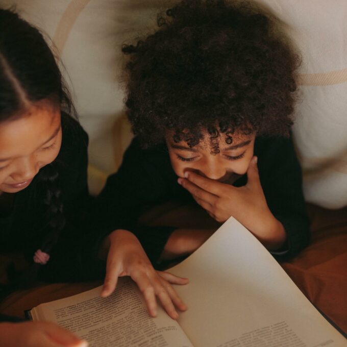 Children reading under the covers